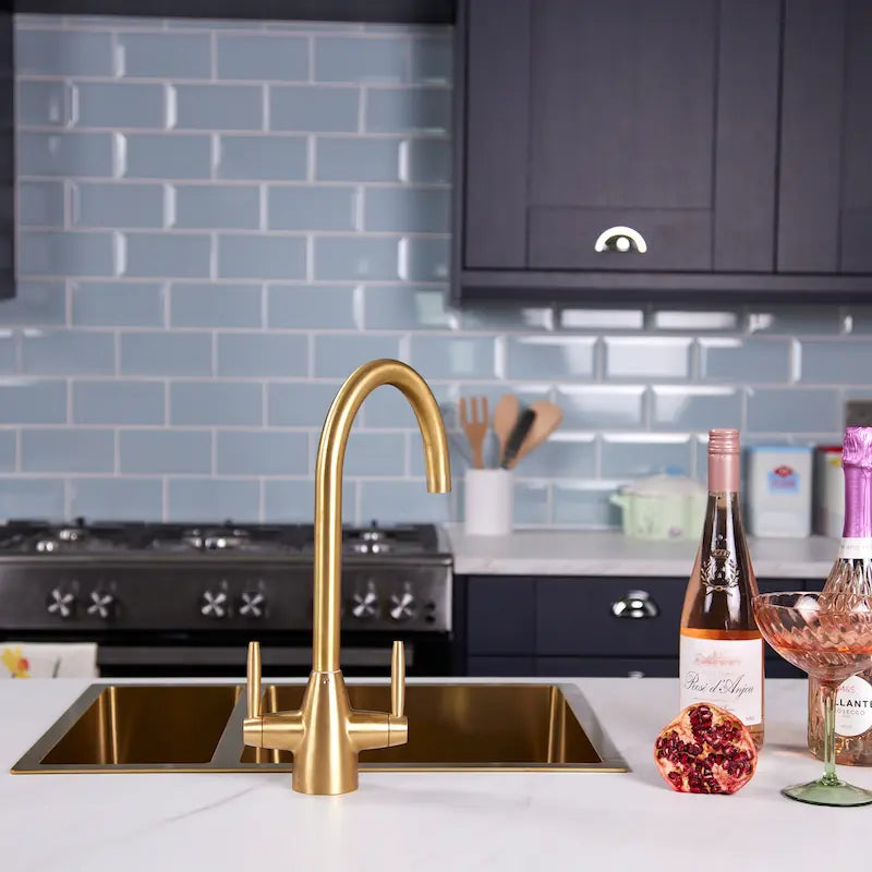 Astrid brushed brass dual lever kitchen tap front view above a gold kitchen sink
