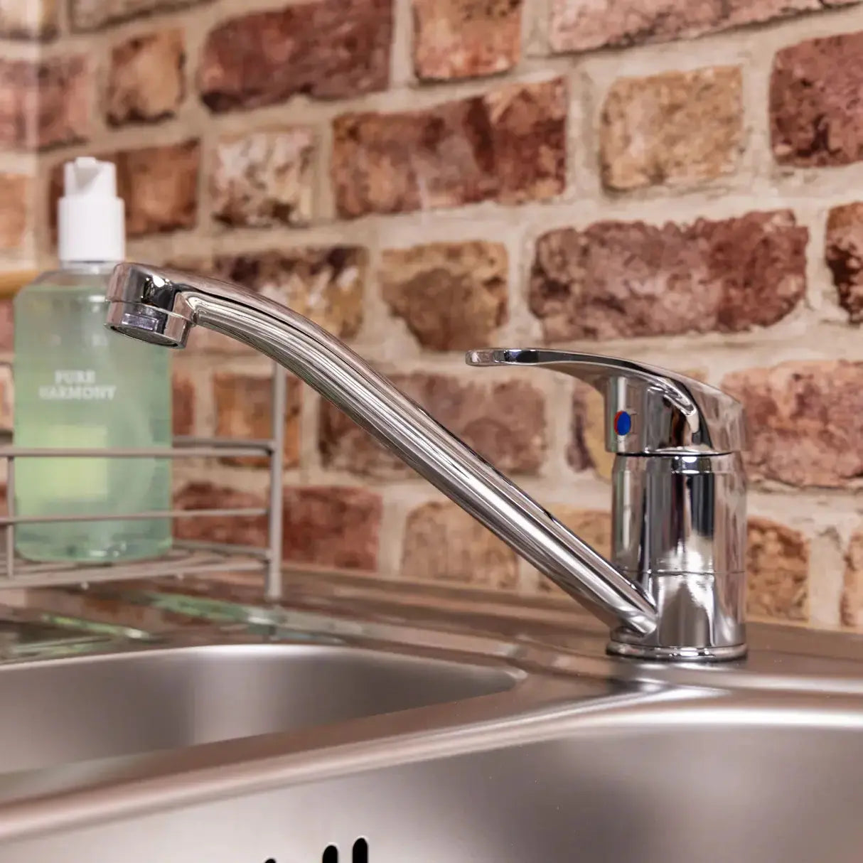 Chrome Vesper single lever kitchen mixer tap on sink and bricks wall background