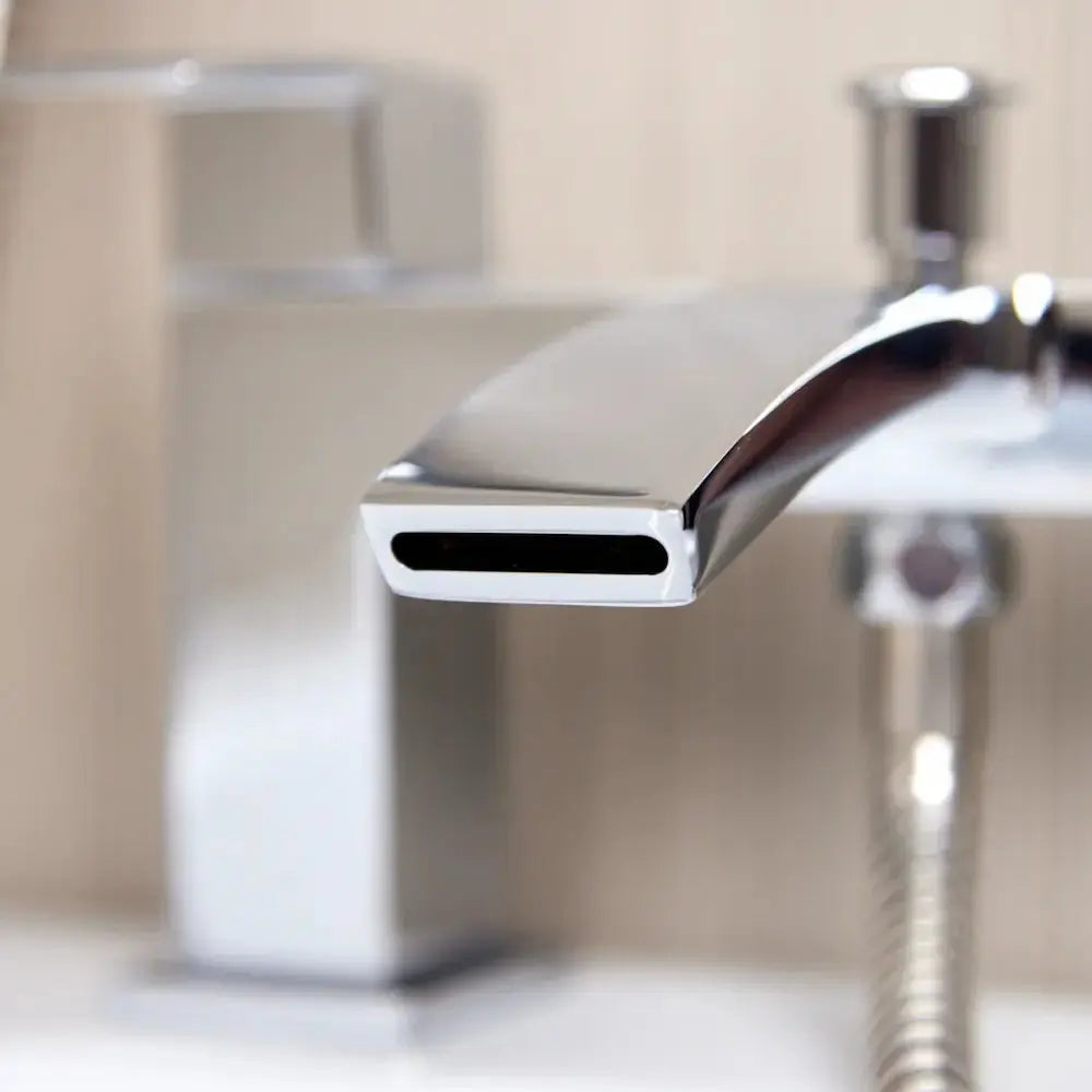 Modern chrome bath shower mixer tap installed with a waterfall spout close up view