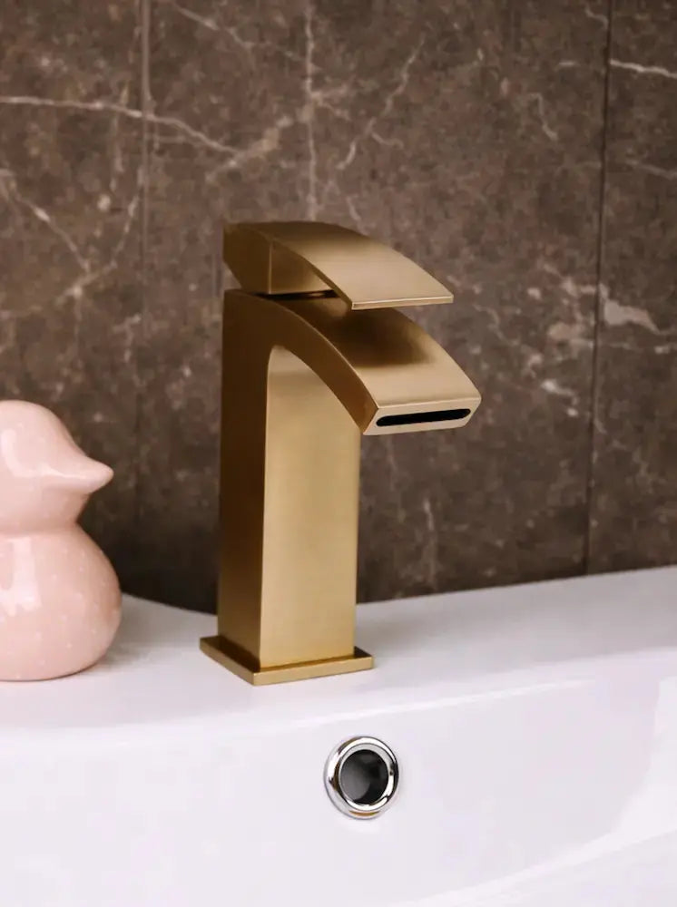 Gold square waterfall basin sink tap Kinlin in Ireland on a marble wall background