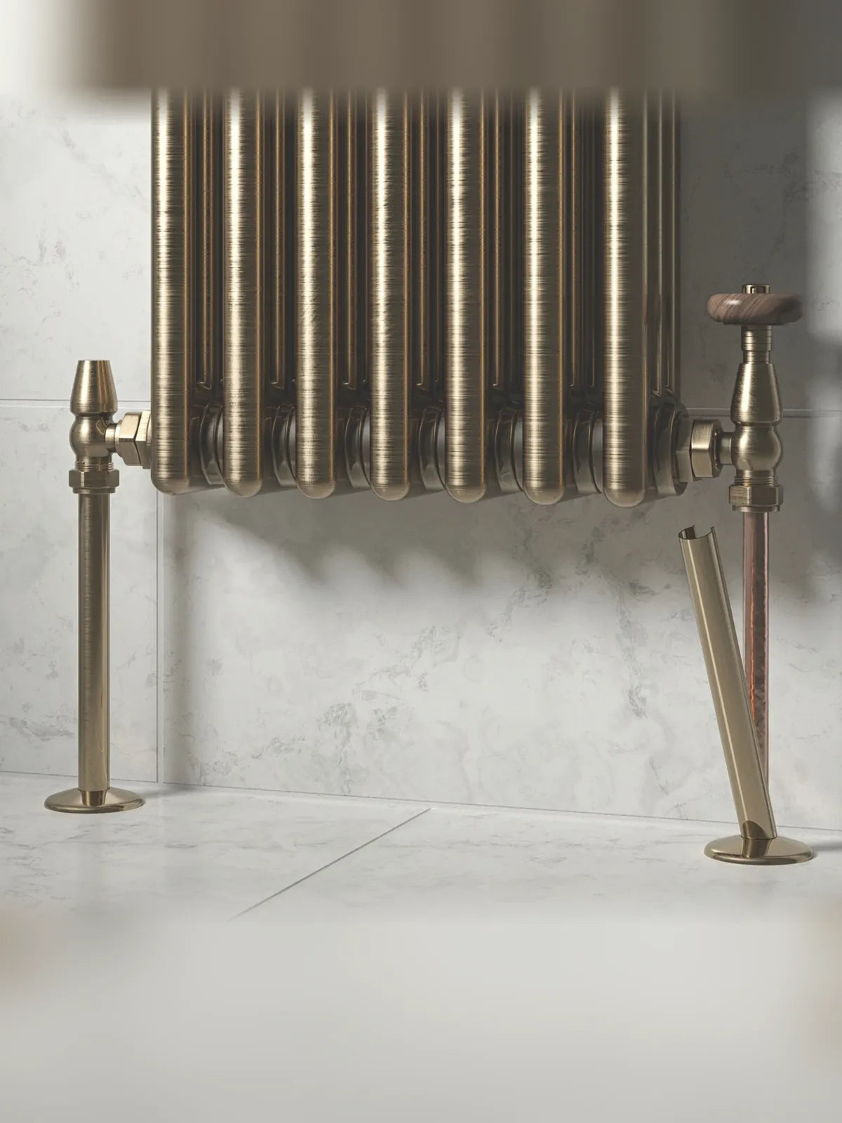Antique brass radiator pipe covers fitted to the pipes of a column radiator with traditional valves