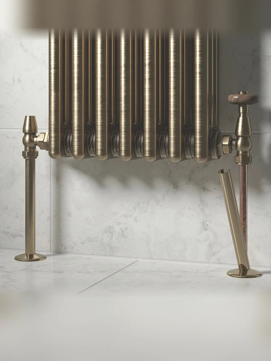 Antique brass radiator pipe covers fitted to the pipes of a column radiator with traditional valves