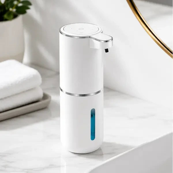 Automatic soap dispenser standing on a marble bathroom basin surround beside folded towels