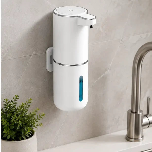Automatic soap dispenser stuck to a tiled kitchen wall on its adhesive plate beside a steel sink tap, no drilling