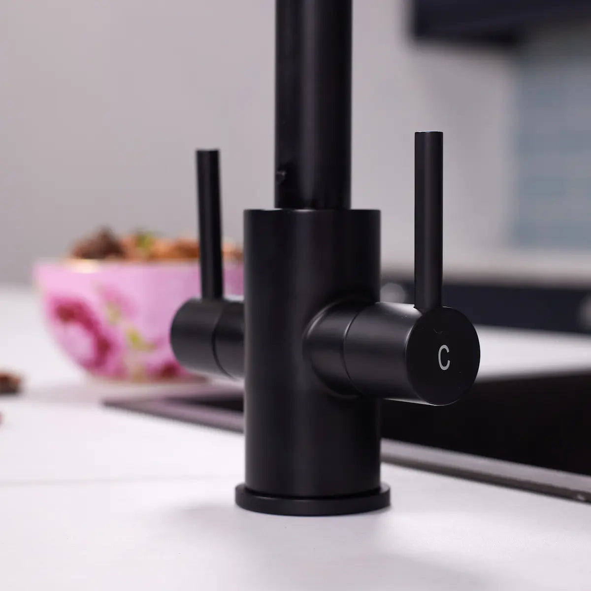 Detail of the two slim levers on the matt black Adria kitchen tap, with the cold lever marked C