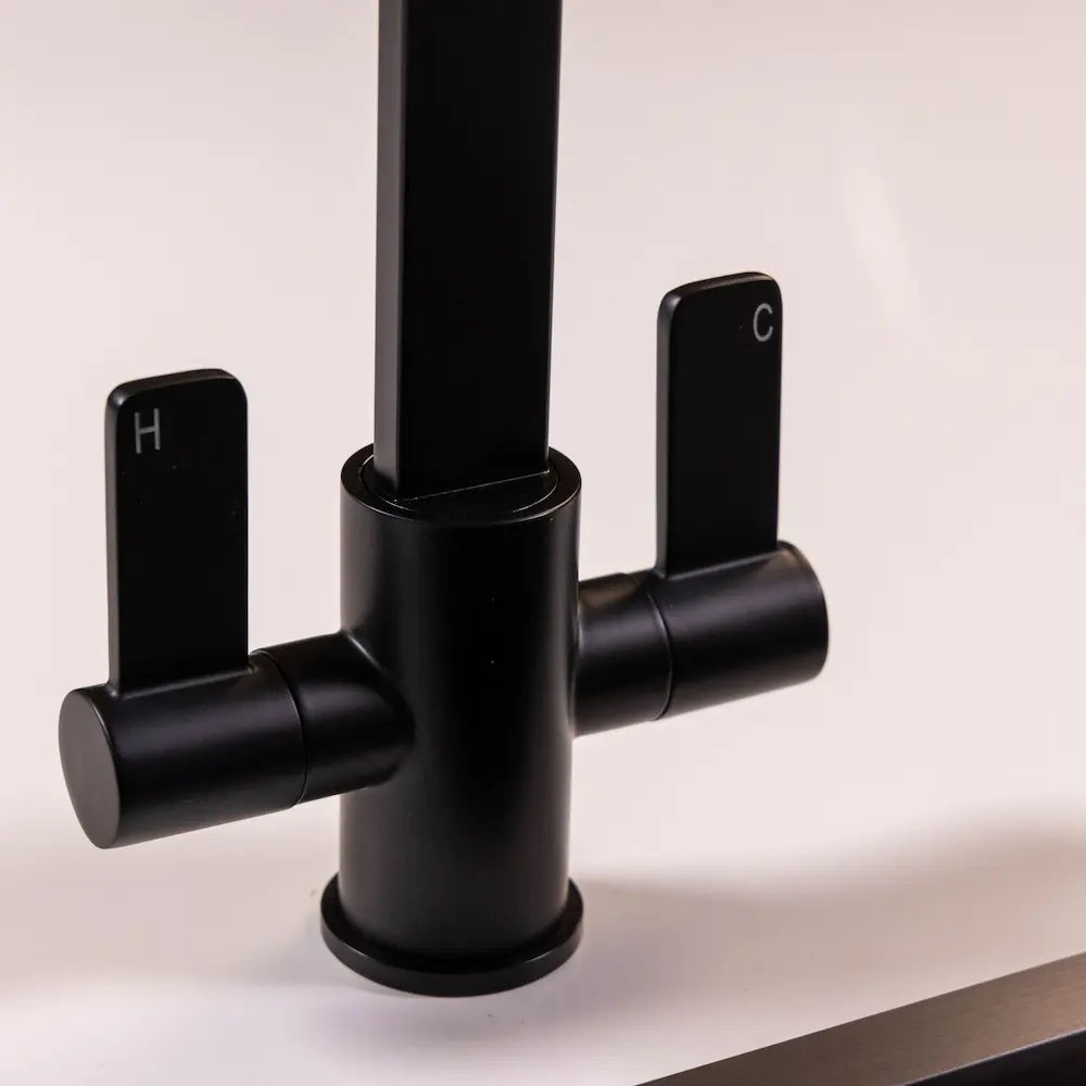 Close view of the two quarter-turn levers on the matt black tap body, marked H for hot and C for cold