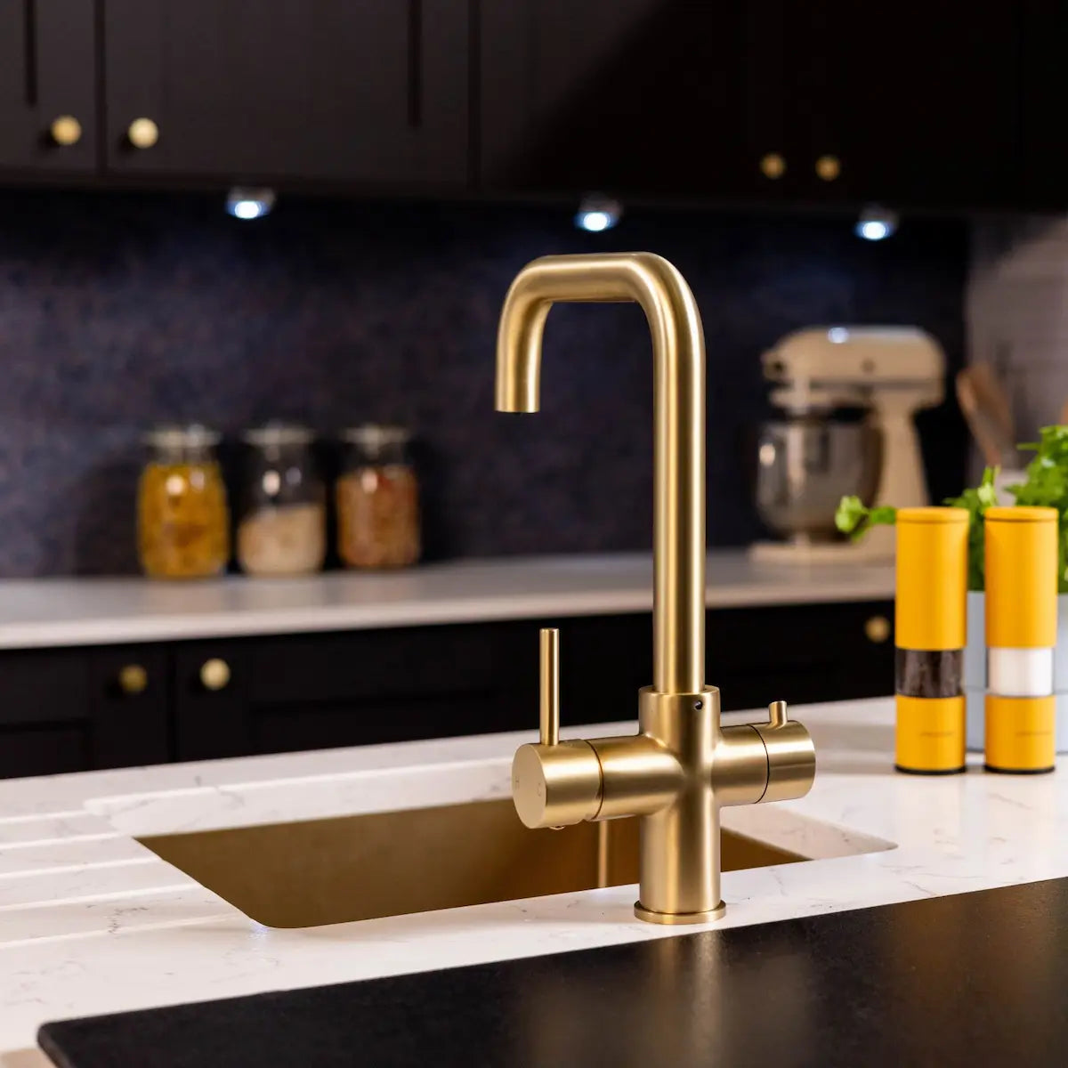 Front view of the brushed brass 3 in 1 boiling tap fitted over a brass undermount sink, showing the squared spout and both levers