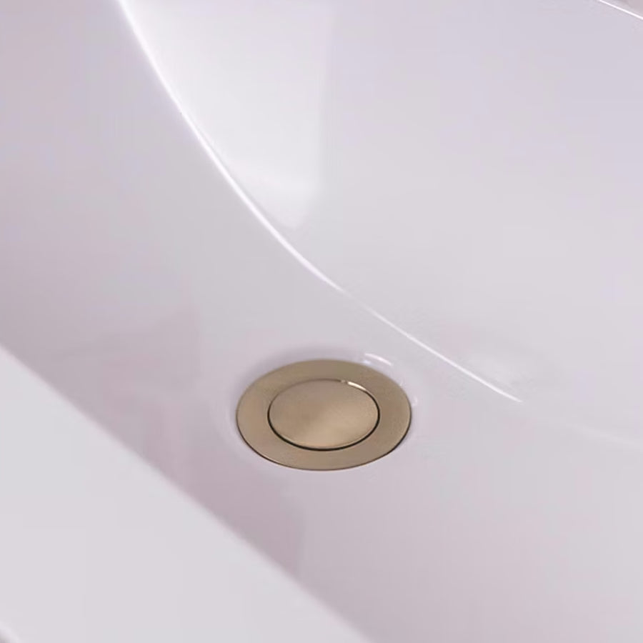 Brushed brass push button basin waste fitted in a white basin with no overflow, beneath a brushed brass mono basin tap