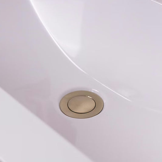 Brushed brass push button basin waste fitted in a white basin with no overflow, beneath a brushed brass mono basin tap