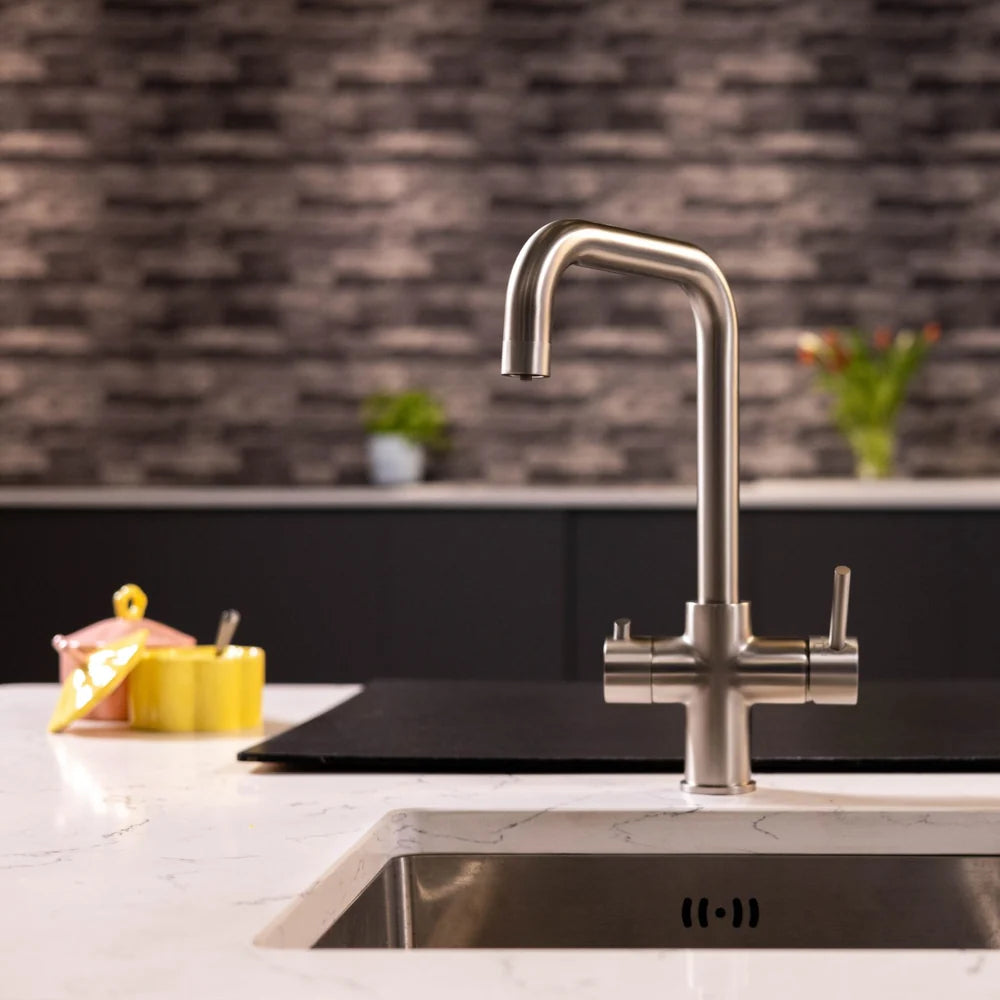 Brushed steel boiling water kitchen tap with a squared swivel spout over an undermount sink on a white marble-effect worktop