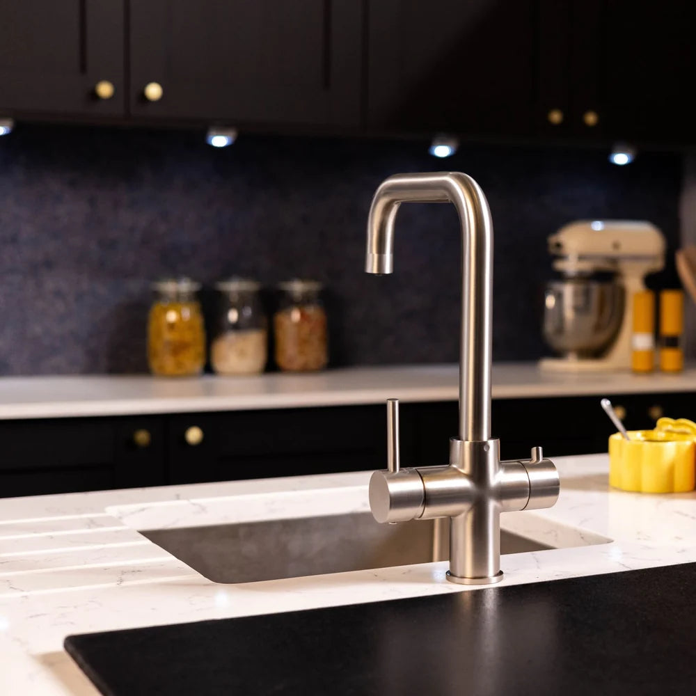 Brushed steel 3 in 1 kettle tap in a dark kitchen with a stand mixer and storage jars behind