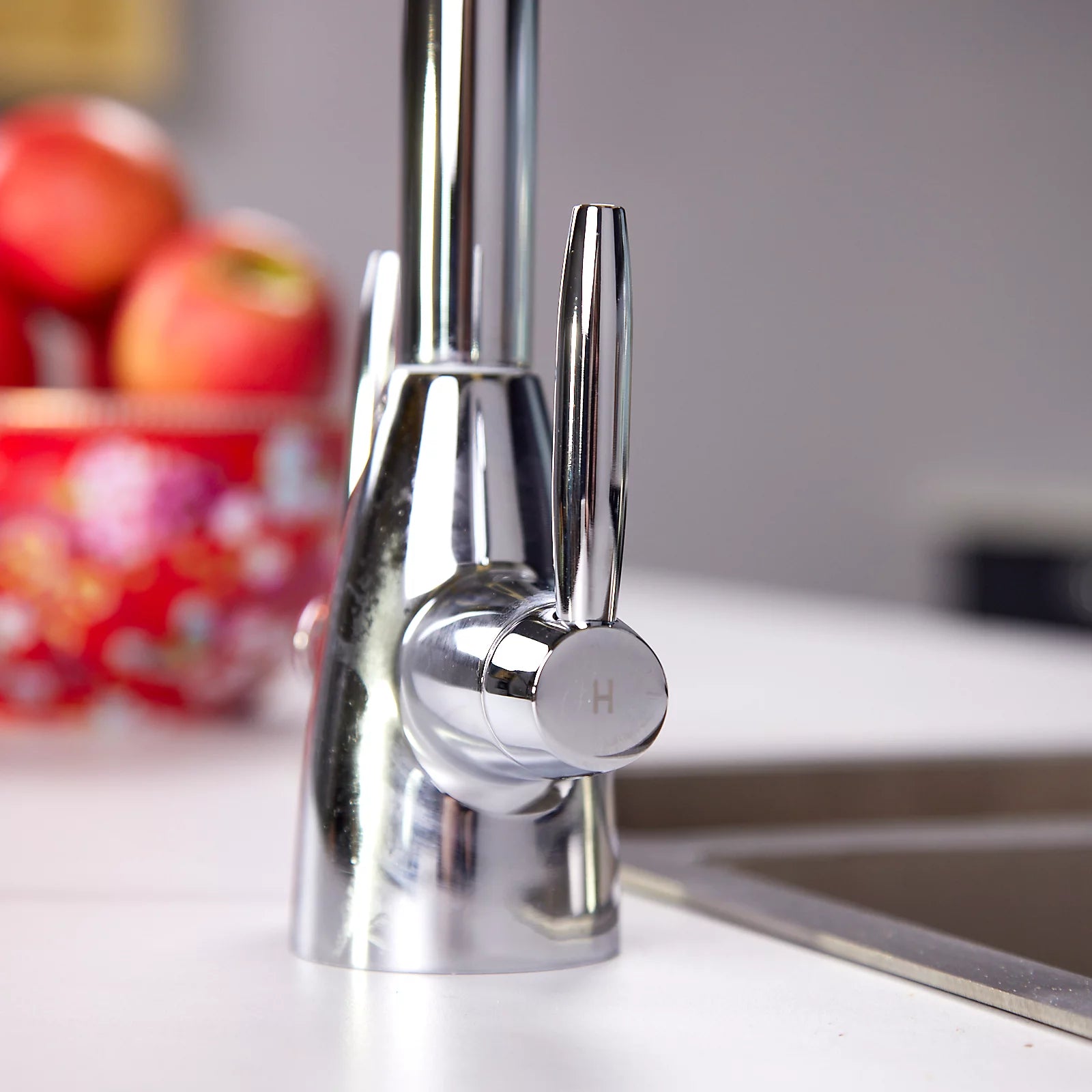 Close view of the chrome quarter-turn lever handles and body of the Astrid dual lever kitchen tap