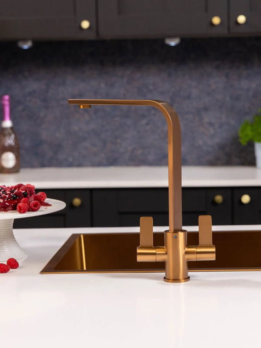 Brushed copper Stroud kitchen tap above a copper-coloured undermount sink in a dark kitchen with a speckled splashback and black units