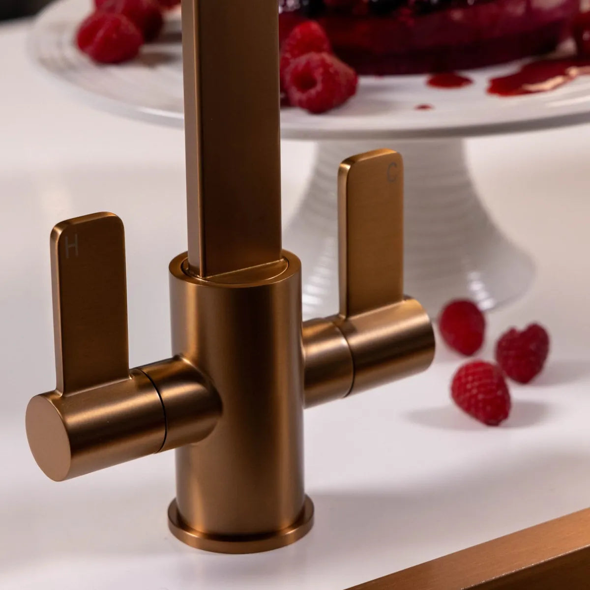 Close view of the two quarter-turn levers on the brushed copper Stroud, with raspberries on the white worktop