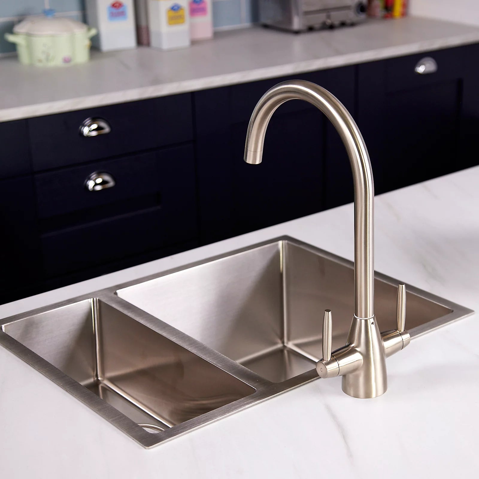 Pewter Astrid kitchen tap beside a double bowl stainless steel sink in a navy shaker kitchen