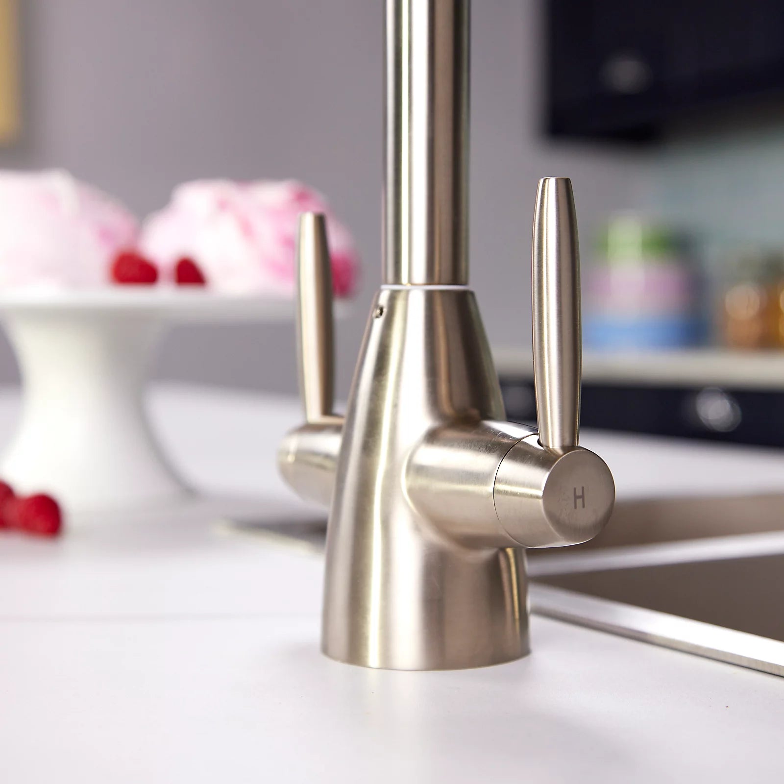 Close view of the brushed pewter lever handles and body of the Astrid dual lever kitchen tap