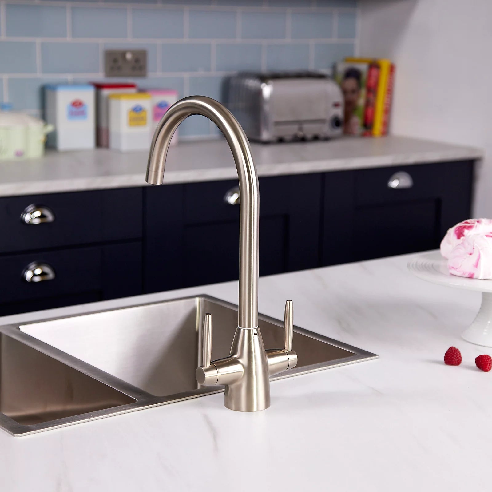 Pewter dual lever kitchen tap viewed from the right on a white marble worktop, with a toaster on the counter behind