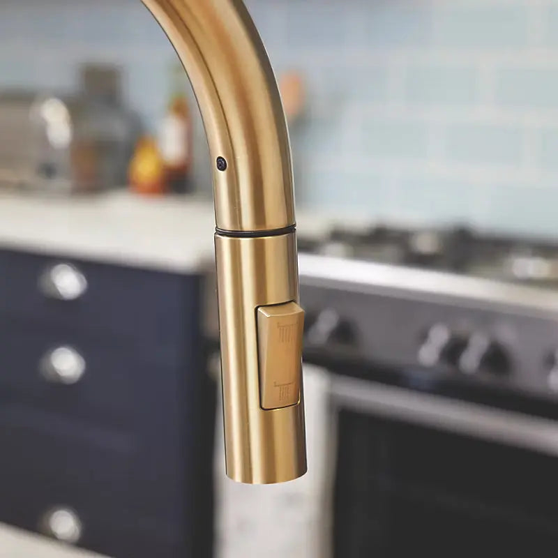 Close-up of brushed brass pull-out kitchen tap showing spray head and finish texture