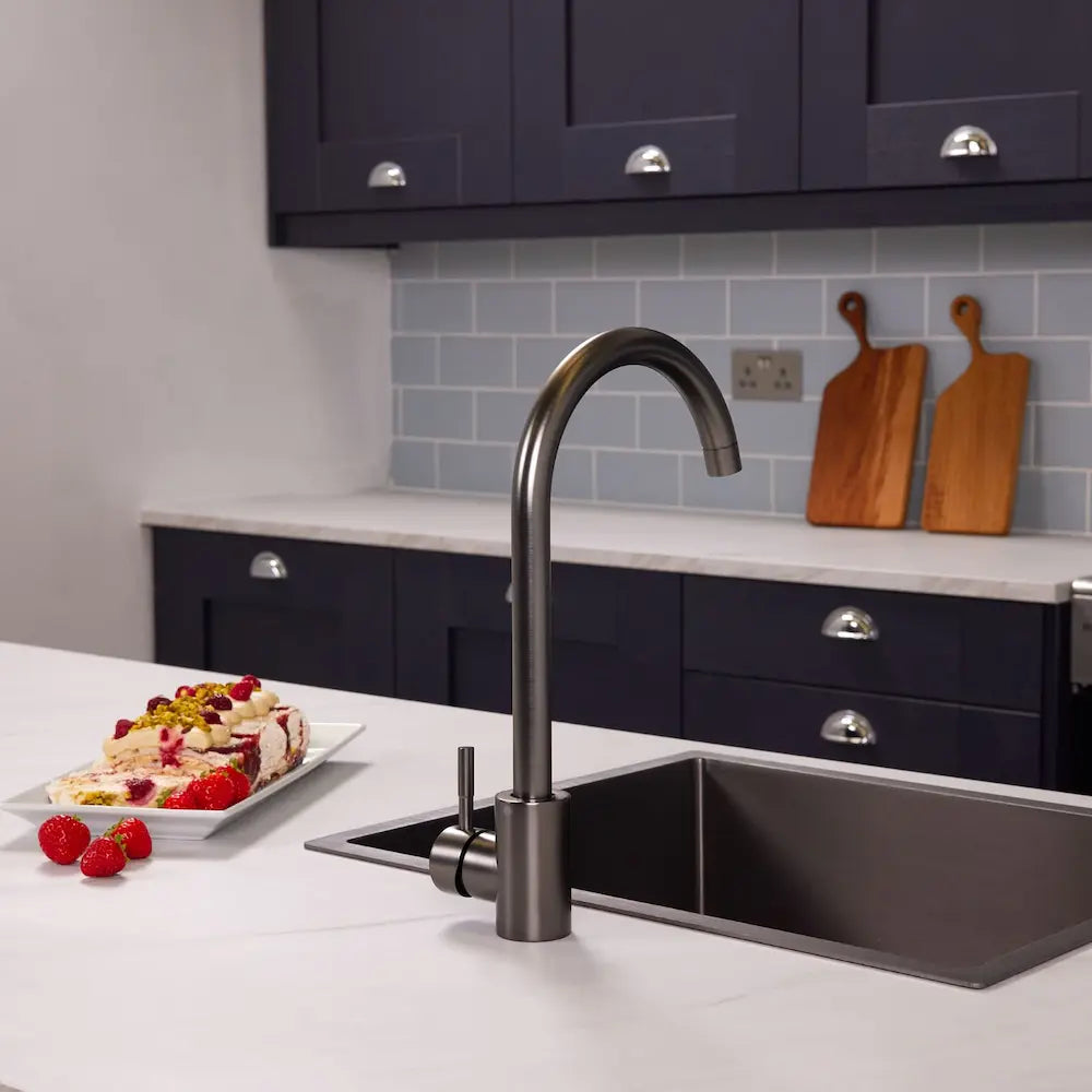 Tivoli gunmetal swan neck kitchen tap above an inset black sink on a white marble-effect worktop