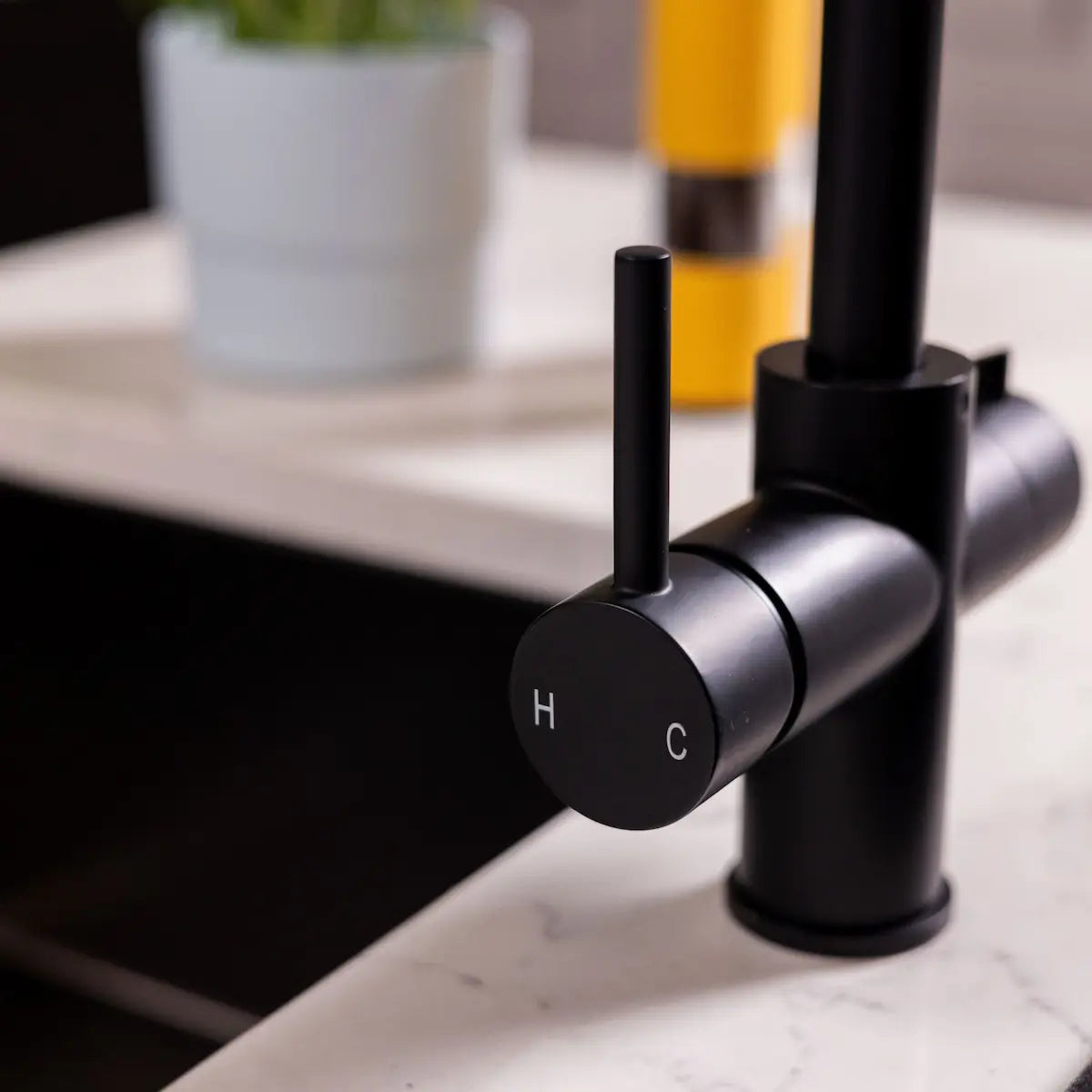 Close view of the standard mixer lever on the matt black tap, marked H and C for hot and cold