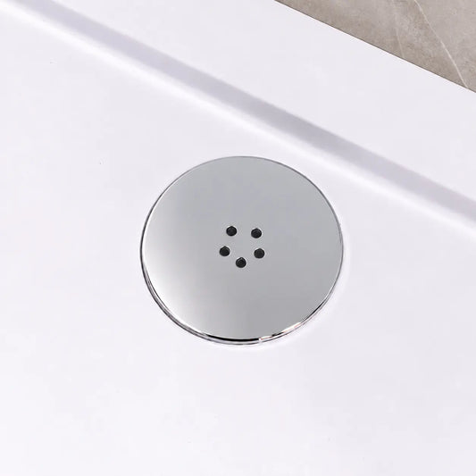 Polished chrome shower waste cover fitted in a white shower tray beside a greige tiled wall