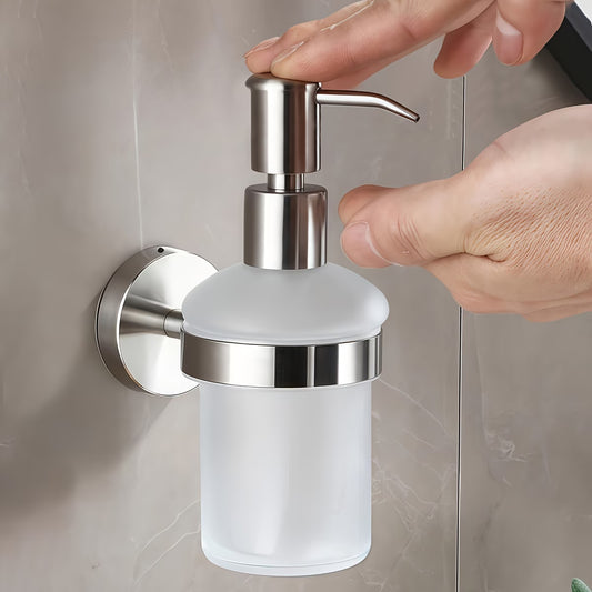 A hand pressing the pump of the wall mounted soap dispenser, fitted to a grey tiled bathroom wall above the basin.